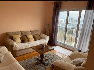 a living room with a couch and a large window at Sea View Budva in Komoševina