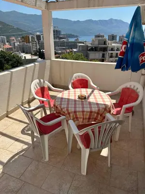 a table and chairs and an umbrella on a balcony at Sea View Budva in Komoševina