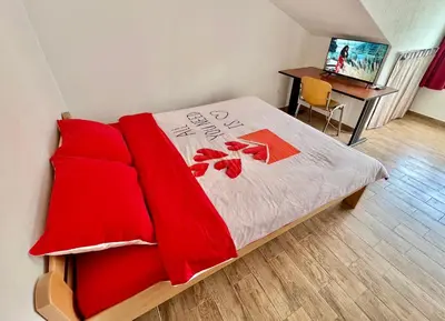 a bedroom with a bed with red pillows and a desk at Homestay LGBT friendly - DOUBLE BED ROOM in Budva