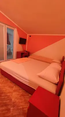 a bedroom with a large bed with a red wall at Pravo mjesto za odmor in Bar