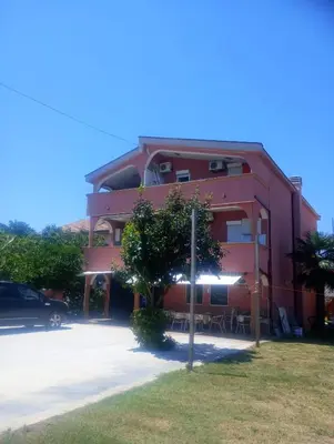 a red building with a tree in front of it at Apartment Asko in Ulcinj