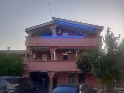 a pink building with cars parked in front of it at Apartment Asko in Ulcinj