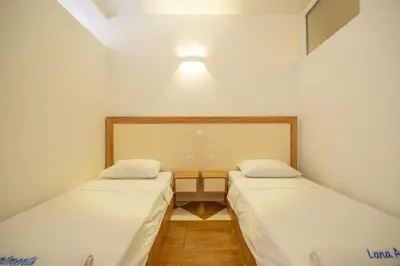 two beds in a room with a light on the wall at Lana Apartments Nr 11 in Ulcinj