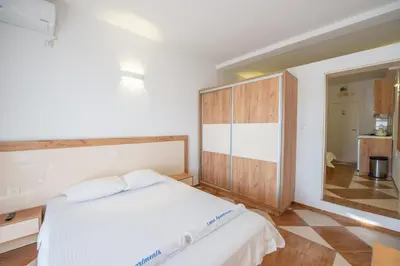 a bedroom with a white bed and a wooden cabinet at Lana Apartments Nr 11 in Ulcinj