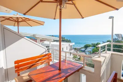 a balcony with a wooden bench and an umbrella at Lana Apartments Nr 11 in Ulcinj