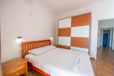 a bedroom with a white bed and a wooden headboard at Lana Apartments Nr 1 in Ulcinj