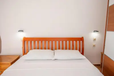 a bed with white sheets and a wooden headboard at Lana Apartments Nr 1 in Ulcinj