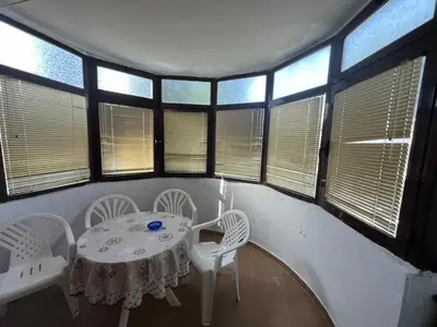 a white table and chairs in a room with windows at Garsonjera Ulcinj in Ulcinj
