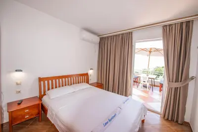 a bedroom with a bed and a balcony with a table at Lana Apartments Nr 3 in Ulcinj