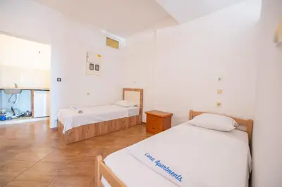 two beds in a room with white walls and wooden floors at Lana Apartments Nr 2 in Ulcinj