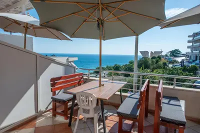 a balcony with a wooden table and chairs and an umbrella at Lana Apartments Nr 2 in Ulcinj