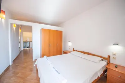 a bedroom with a large white bed and wooden cabinets at Lana Apartments Nr 2 in Ulcinj