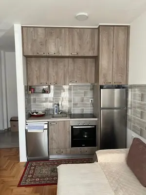 a kitchen with wooden cabinets and a stainless steel refrigerator at Apartment Aleksa in Bar