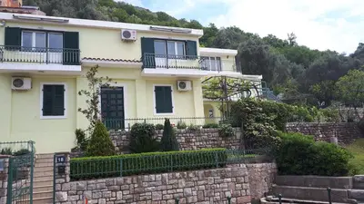 a yellow house with a stone wall at Apartments Simo in Petrovac na Moru