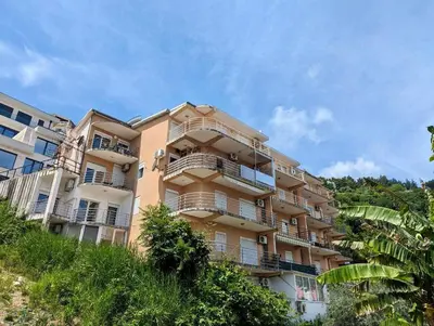 a large apartment building on a hill with trees at Sea View Budva in Budva