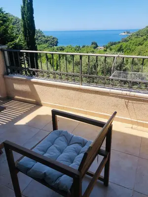 a chair on a balcony with a view of the ocean at Bay View Apartments in Petrovac na Moru
