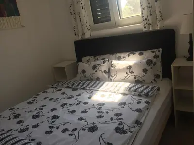 a bed with a black and white comforter and a window at Bay View Apartments in Petrovac na Moru