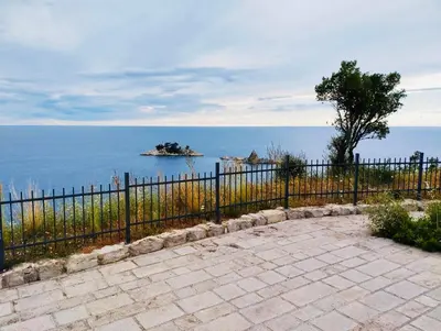 a fence next to the ocean with an island in the water at Bay View Apartments in Petrovac na Moru
