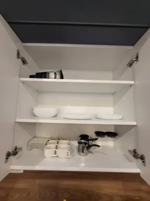 a kitchen with white shelves with dishes and a sink at Master apartment in Kruševac