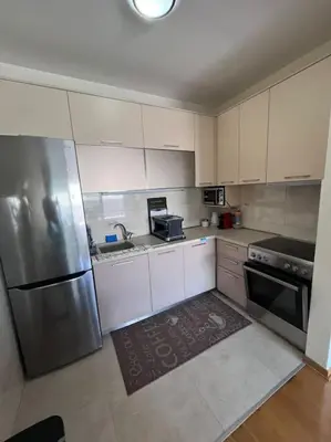 a kitchen with white cabinets and a stainless steel refrigerator at Charming and nature surrounded in Podgorica