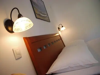 a bedroom with a bed with a wooden headboard and lights at Apartments Maris in Petrovac na Moru