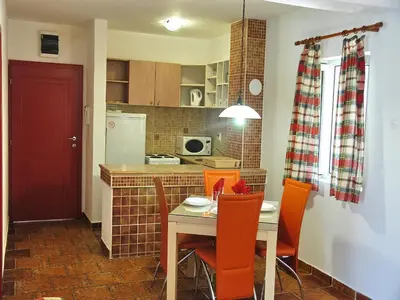 a kitchen with a table and chairs and a red door at Apartments Maris in Petrovac na Moru