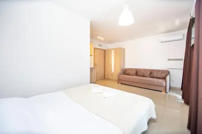 a bedroom with a white bed and a couch at Apartments Vila Anastasia in Budva