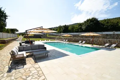 a swimming pool with chairs and umbrellas next to a pool at Baloci hills in Gornja Gorica