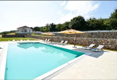 a swimming pool with chairs and an umbrella at Baloci hills in Gornja Gorica