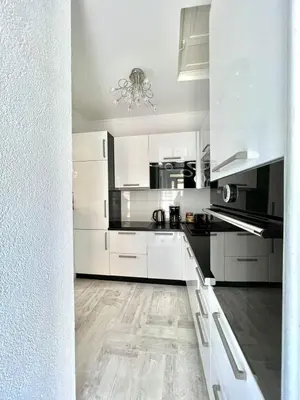 a white kitchen with white cabinets and a wooden floor at Apartment Kiki in Kotor