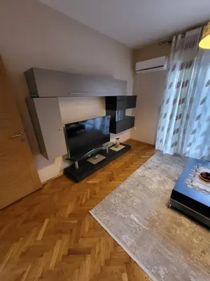 a living room with a flat screen tv and a wooden floor at Centre Podgorica apartment in Podgorica