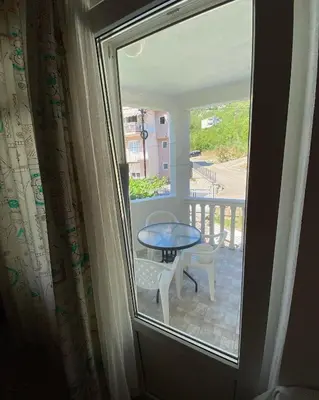a room with a window and a table on a balcony at Apartmani Jovanovic Canj in Čanj