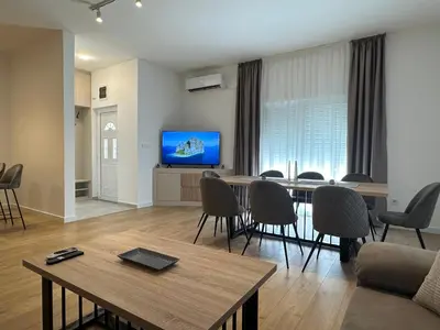 a living room with a table and chairs and a television at Fratelli Apartments in Tuzi