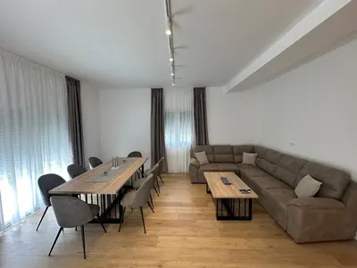 a living room with a couch and tables and chairs at Fratelli Apartments in Tuzi