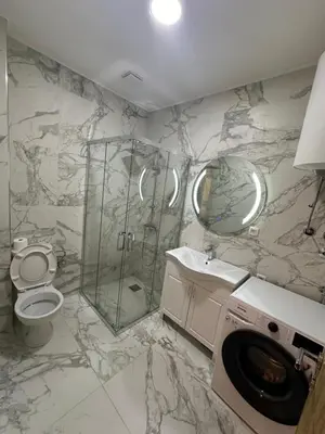 a marble bathroom with a toilet and a shower at Fratelli Apartments in Tuzi