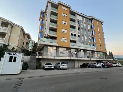 a large building with cars parked in a parking lot at AS Apartment in Podgorica