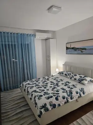 a bedroom with a bed with a blue and white comforter at AS Apartment in Podgorica