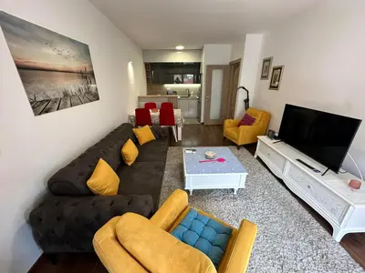 a living room with a black couch and yellow chairs at Sunshine Master apartment in Podgorica