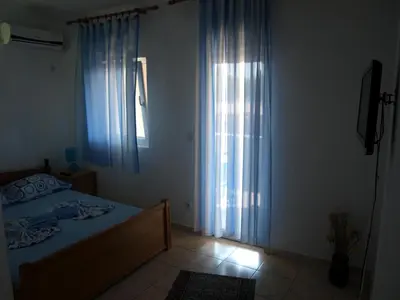 a bedroom with a bed and a window with curtains at Friendly House in Ulcinj