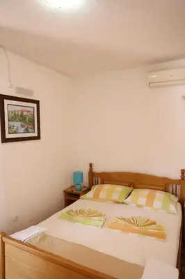 a bedroom with a bed with a wooden headboard at Friendly House in Ulcinj
