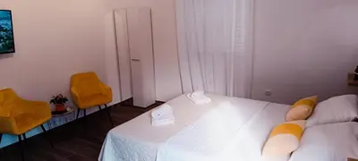 a bedroom with a white bed and two chairs at Apartman Luka in Trojica