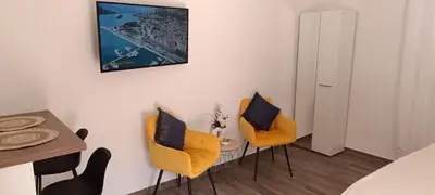 a bedroom with two yellow chairs and a table at Apartman Luka in Trojica
