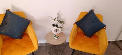 two orange chairs with pillows and a table with a vase at Apartman Luka in Trojica