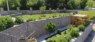 a garden with a stone wall and a table with plants at Apartman Lara 3 in Trojica