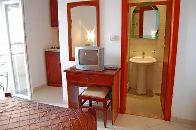 a bathroom with a tv on a table with a sink at Vila Maslina Guesthouse in Budva