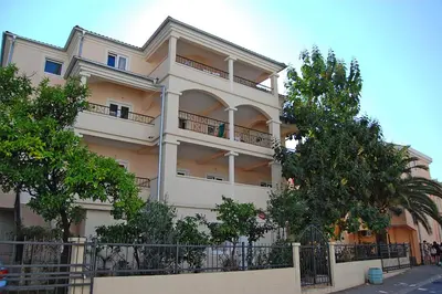 a large white building with trees in front of it at Vila Maslina Guesthouse in Budva