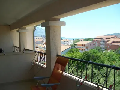 a balcony with two chairs and a view of a city at Vila Maslina Guesthouse in Budva