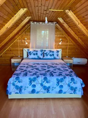 a bedroom with a blue bed in a wooden cabin at Amazing &Magic houses- Ada Bojana in Gornji Štoj