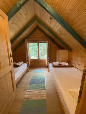 an attic room with two beds and a window at Amazing &Magic houses- Ada Bojana in Gornji Štoj