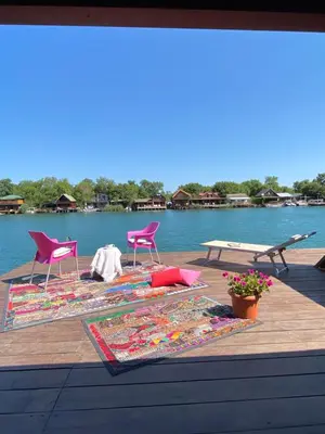 two chairs and rugs on a wooden deck with water at Amazing &Magic houses- Ada Bojana in Gornji Štoj